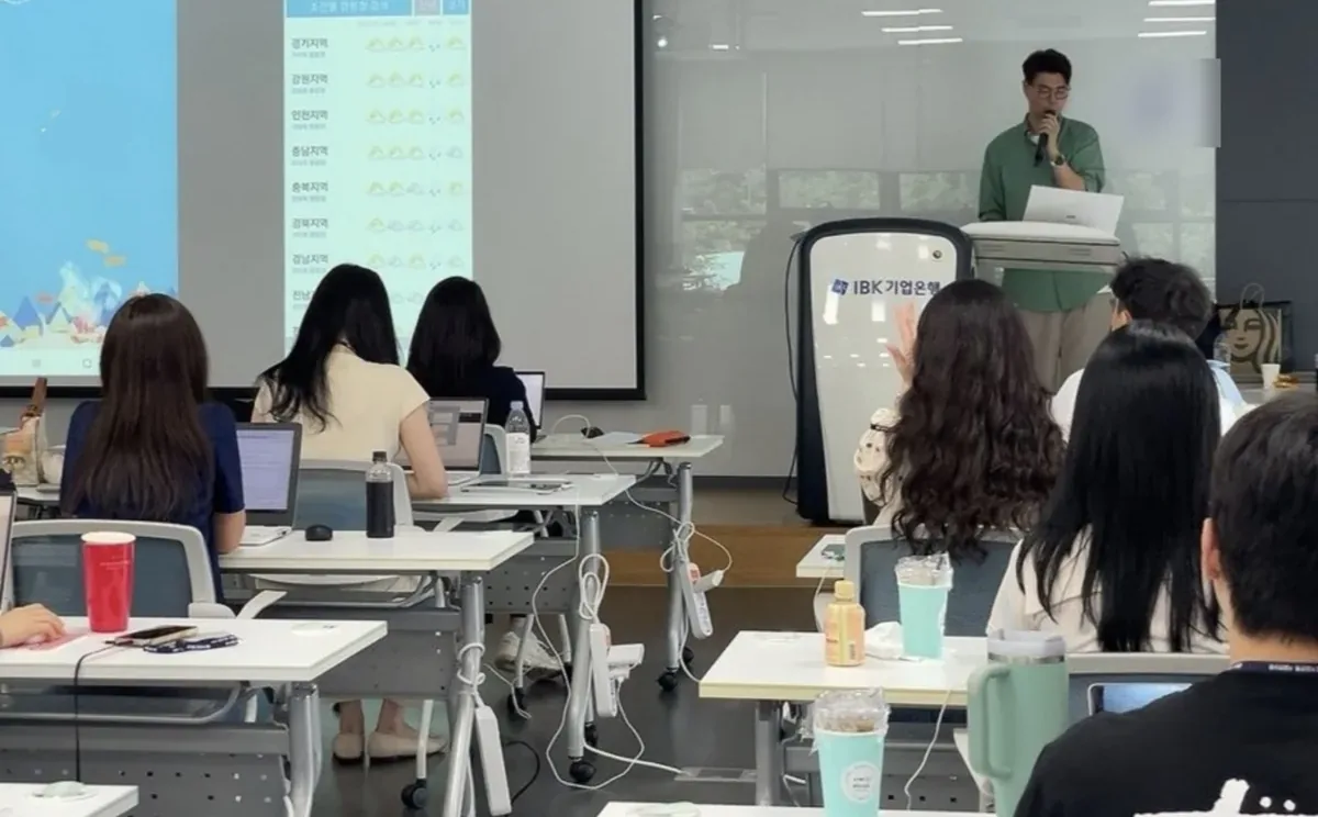 IBK기업은행 실무자 대상 슈퍼플래닝 UX강의 현장 — 강사가 앱 화면 사례를 설명하고 참석자들이 노트북으로 실습하는 기업 출강 강의실